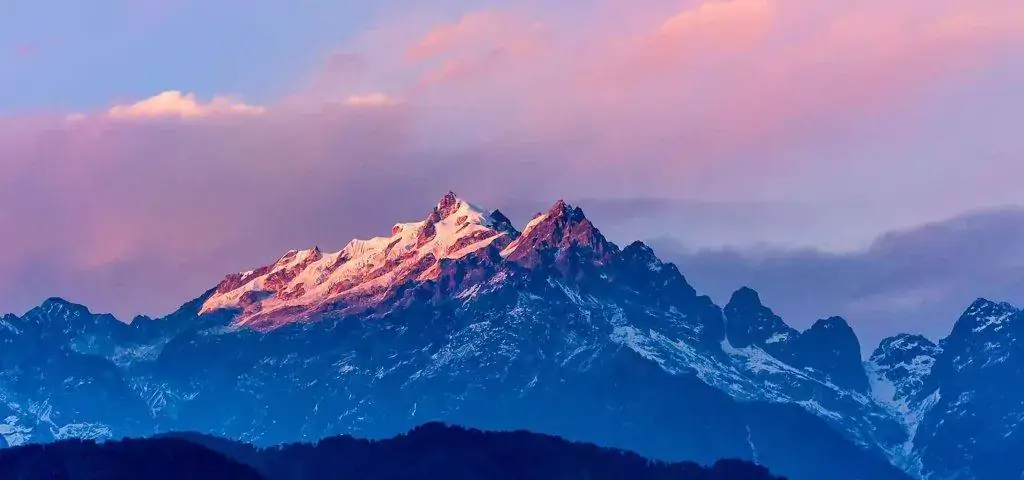Majestic mountain peaks bathed in pinkish light with a pink and purple sky, a must-see for tour operators in Kolkata.