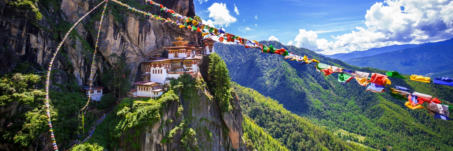 Tiger's Nest Monastery on a cliff in Bhutan with prayer flags, a sight showcased by tour operators in Kolkata.