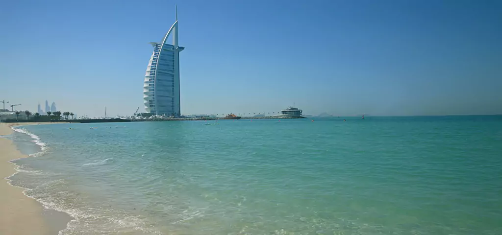 Pristine beach with turquoise waters and modern skyscraper, a serene scene offered by tour operators in Kolkata.